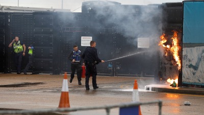 عناصر من الجيش وحرس الحدود البريطانية يطفئون حريقاً في مركز دوفر بعد الهجوم عليه بقنبلة حارقة (رويترز)