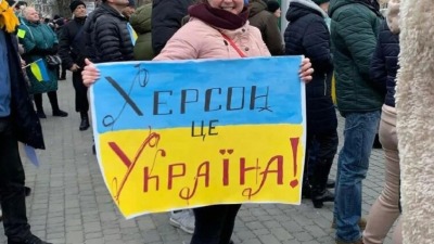 سيدة تحمل علم أوكرانيا ومكتوب عليه "خيرسون أوكرانية" (تويتر)