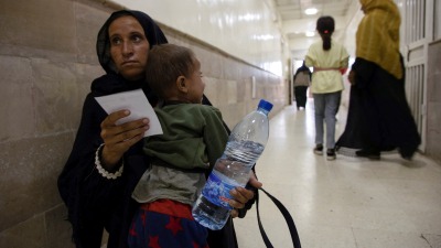 أم سورية تحمل طفلها الذي شُخصت إصابته بالكوليرا في مستشفى بمدينة الحسكة - 24 أيلول 2022 (رويترز)