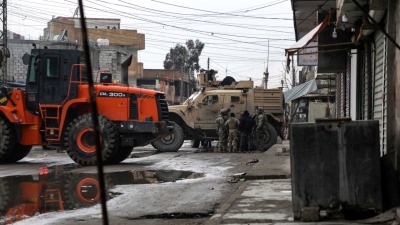جنود أميركيون وعناصر في "قسد" يقفون بجوار جرافة ومركبات عسكرية بحي غويران في الحسكة - كانون الثاني 2022 (AFP)