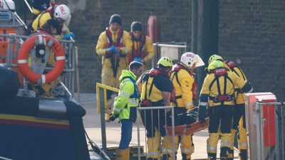 طواقم الإنقاذ يحملون جثث طالبي لجوء على نقالة بعد عودتهم إلى ميناء دوفر البريطاني - 14 كانون الأول (رويترز)