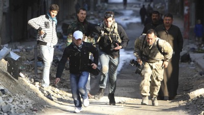 صحفي سوري يساعد مراسلين أجانب على تجاوز مناطق خطرة في حي صلاح الدين بمحافظة حلب في سوريا عام 2012 (رويترز)