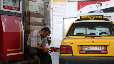 سائق تاكسي يملئ سيارته بالوقود في إحدى المحطات بالعاصمة دمشق - رويترز