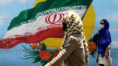 نساء يمشين بجانب رسمة جدارية للعلم الإيراني في أحد شوارع طهران - 17 حزيران 2021 (AFP)