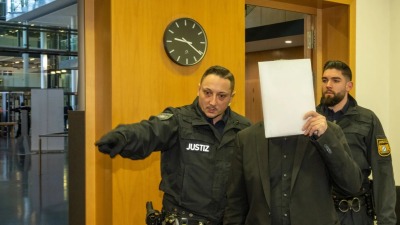 عنصرين من الشرطة يقودان الأب المتهم إلى قاعة المحكمة (Foto: Stefan Puchner/dpa)