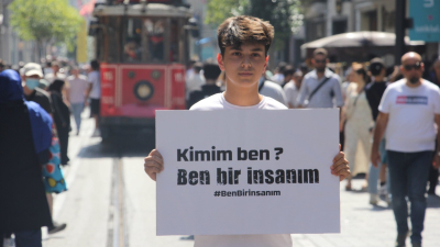  شاب تركي يرفع لافتة في إسطنبول تضامناً مع الفتى السوري أحمد كنجو، كتب عليها: "من أنا؟ أنا إنسان" - 21 تموز 2022 (أنترنت)