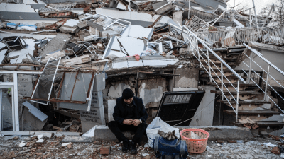 رجل يجلس على أنقاض منزله المدمر بفعل الزلزال في هاتاي التركية - GETTY