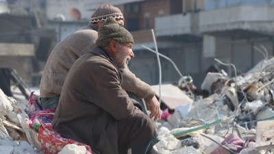 مسنان يجلسان على أنقاض المنازل المدمرة من جراء الزلزال في بلدة عزمارين بريف إدلب - 14 شباط 2023 (الدفاع المدني السوري)