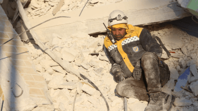 عنصر من الدفاع المدني السوري يجلس على أنقاض منزل مدمر في مدينة حارم - (الدفاع المدني)
