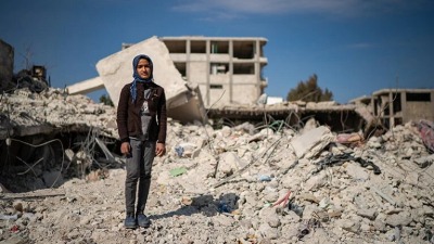 طفلة تقف فوق ركام الأبنية التي دمرها الزلزال في سوريا