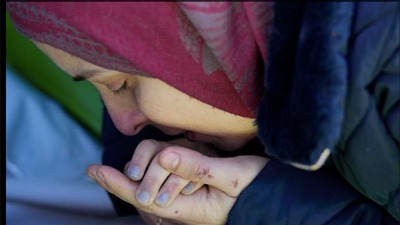 أم سورية تقبل يد ابنتها الصغيرة التي فقدت حياتها جراء الزلزال في جنوبي تركيا (AP)