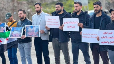 نشطاء في معبر باب الهوى يحملون لافتات منددة باستهداف "الجندرما" التركية للاجئيين السوريين (فيس بوك/Abdul Aziz Baraa)