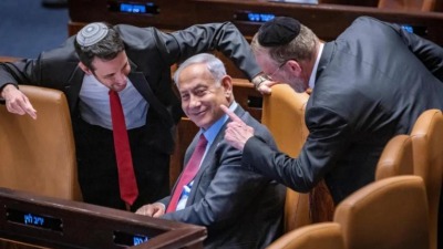بنيامين نتنياهو رئيس الوزراء الإسرائيلي في الكنيست حوله نائبان من كتلة اليمين، 13 آذار/مارس 2023 (هأرتس)