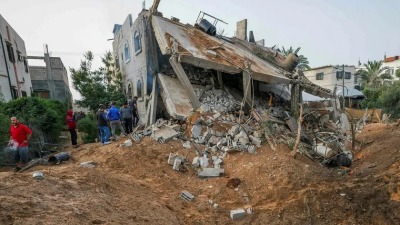 فلسطينيون يتفقدون مبنى دمره القصف الإسرائيلي في دير البلح وسط قطاع غزة، 12 أيار/مايو 2023 (AFP)