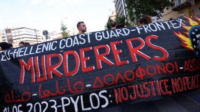 متظاهرون يرفعون لافتة خلال مظاهرة بعد حطام سفينة مهاجرين قاتلة قبالة اليونان ، في أثينا 