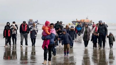 مجموعة من المهاجرين يسيرون على شاطئ دونجينيس بالمملكة المتحدة