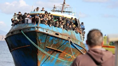 لاجئون يقفون على قارب صيد بعد عملية إنقاذ خارج جزيرة كريت في اليونان -22 تشرين الثاني 2022 (رويترز)