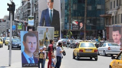 ملصقات لصور رئيس النظام السوري بشار الأسد تملأ شوارع وساحات دمشق (رويترز)