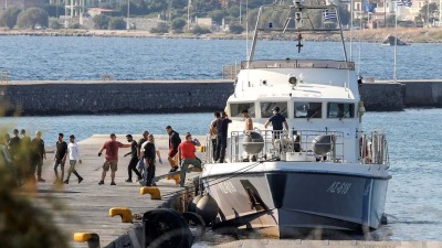مهاجرون ينزلون من سفينة تابعة لخفر السواحل اليوناني في ميناء ميتيليني (رويترز)