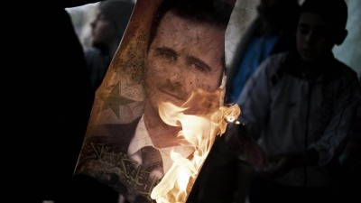 إشعال النار في صورة كبيرة لبشار الأسد كانت منصوبة في ساحة تشرين وسط السويداء - AFP