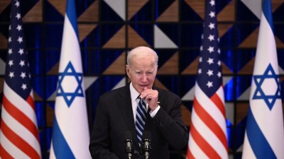 الرئيس الأميركي جو بايدن وخلفه الأعلام الأميركية والإسرائيلية