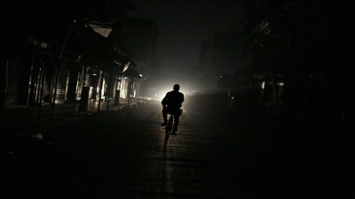 رجل يقود دراجته في إحدى ضواحي العاصمة دمشق خلال انقطاع التيار الكهربائي - AFP