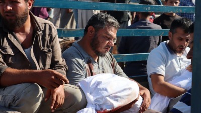 رجل يحمل جثمان طفله بعد مقتله بقصف للنظام السوري على قرية القرقور بريف حماة - الدفاع المدني