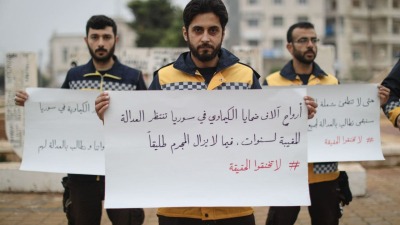 متطوعون في الدفاع المدني يرفعون لافتات تطالب بمحاسبة النظام على استخدام الأسلحة الكيميائية