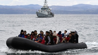 لاجئون في بحر إيجة وخلفهم سفينة تتبع لوكالة "فرونتكس" (AFP)