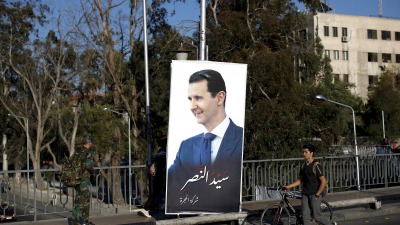 شابان وصورة لـ بشار الأسد في إحدى الطرقات - إنترنت