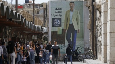 لافتة تحمل صورة رئيس النظام السوري بشار الأسد معلقة على جدار في سوق الحميدية في دمشق- أيلول 2023 (AFP)