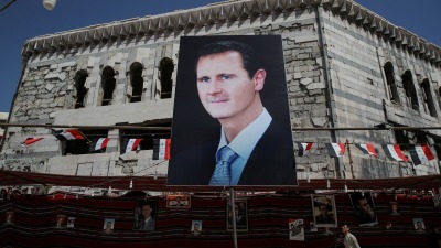 صورة لـ بشار الأسد على مبنى مدمر في مدينة دوما بريف دمشق (رويترز)