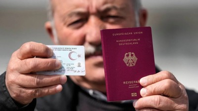 عجوز تركي يحمل هويته الوطنية بيد وباليد الأخرى جواز سفره الألماني - المصدر: إيكونوميست