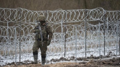 أحد عناصر حرس الحدود البولندي عند سياج من الأسلاك الشائكة على الحدود
