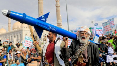 A Yemeni demonstrator carries a mock missile during a march in the capital, Sanaa, which is controlled by the Houthis, on March 8, 2024 (AFP)