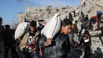 Palestinians carry bags of flour in Gaza