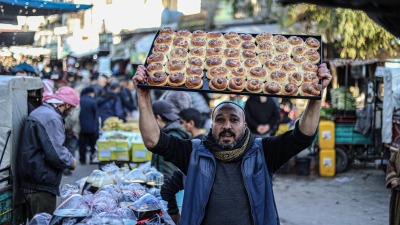 بائع يبيع الخبز الرمضاني التقليدي في سوق في اليوم الثالث من رمضان في أريحا، إدلب، سوريا في 13 مارس/آذا