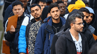 مهاجرون يصطفون في مركز الوصول لطالبي اللجوء في برلين (رويترز)