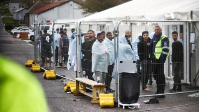 أشخاص يقفون داخل منطقة مسيجة داخل مركز لمعاملة المهاجرين في مانستون بالمملكة المتحدة (رويترز)