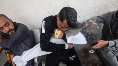 أب فلسطيني يحمل جثة إحدى ابنتيه بعد مقتلهما في قصف إسرائيلي على مشفى النجار في رفح ـ AFP