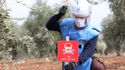 متطوع في الدفاع المدني السوري يزرع لافتة تحذيرية من الألغام